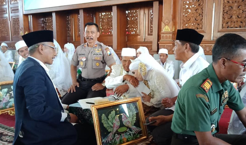 Sejumlah pasangan saat mengikuti nikah massal di Pendopo Krido Manunggal Tuban. Tampak pengantin pria yang sudah berumur sedang dicium tangannya oleh mempelai wanitanya.