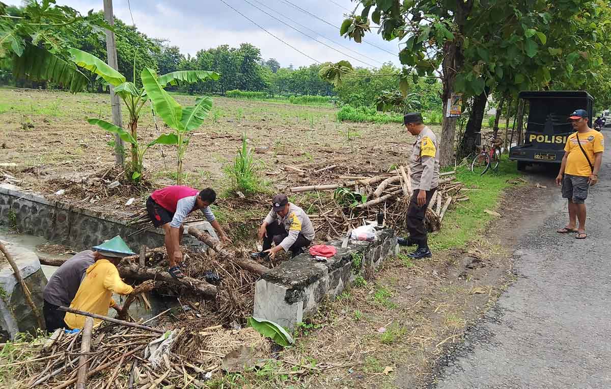 Petugas dari Polres Ngawi saat membantu warga membersihkan saluran air yang terkena limbah.