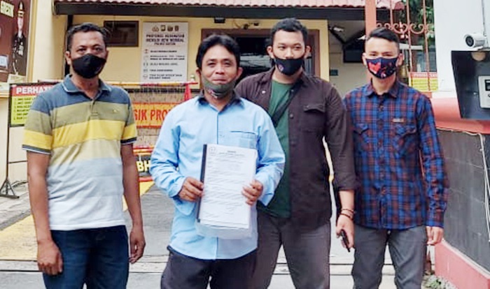 Aris Gunawan (memegang surat laporan) usai melapor di Polres Gresik. foto: ist.
