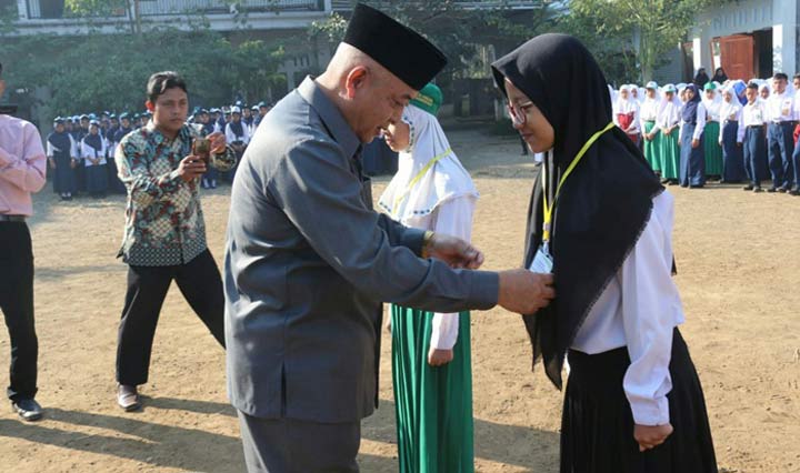Plt Bupati Malang saat mengalungkan tanda PLS kepada seorang siswi.