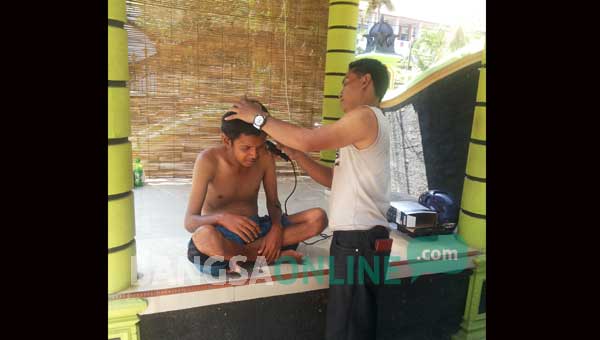 Ghani saat mencukur orang gila yang mulai melunak kepadanya. foto: andi sirajudin/ BANGSAONLINE
