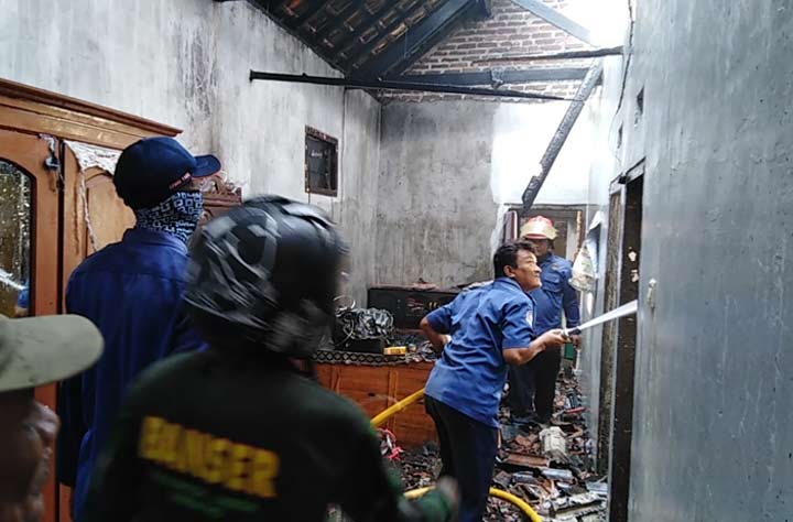Petugas melakukan pembasahan terhadap sisa-sisa api.