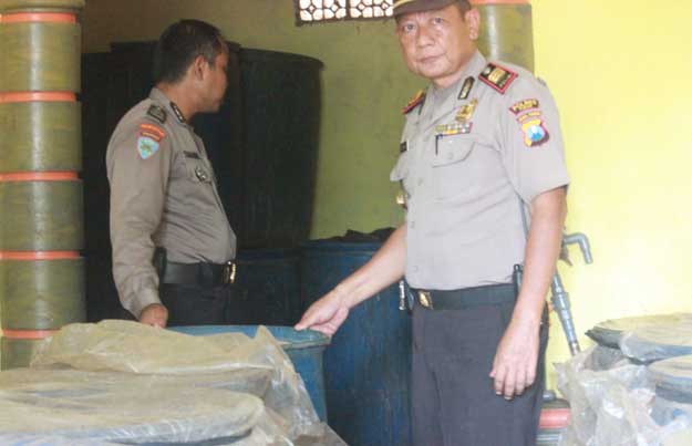 Kapolsek Semanding AKP Desis Susilo menunjukkan drum berisi arak baceman. foto: GUNAWAN WIHANDONO/ BANGSAONLINE
