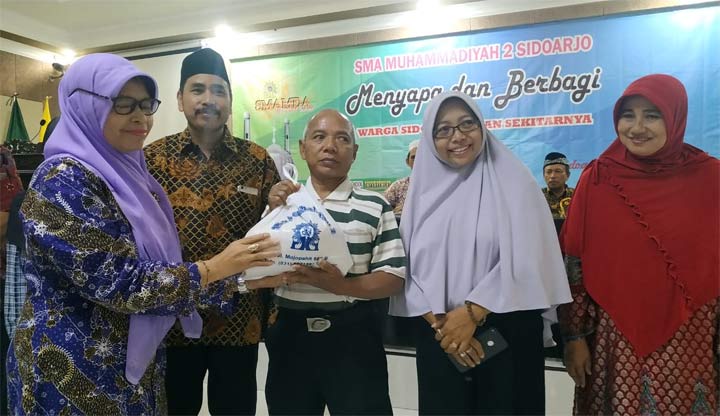 SIMBOLIS: Kepala SMAMDA Wigatiningsih menyerahkan bingkisan kepada warga Sidowayah, Rabu (29/5). foto: MUSTAIN/ BANGSAONLINE