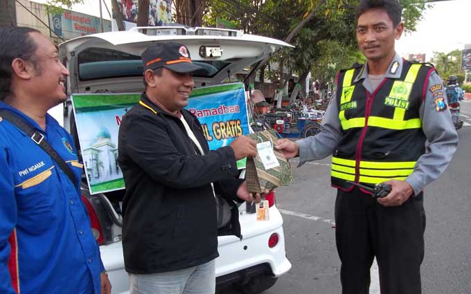Ketua PWI Nganjuk Ristika W saat membagikan takjil kepada anggota kepolisian yang bertugas mengamankan arus mudik lebaran. foto: BAMBANG DJ/ BANGSAONLINE