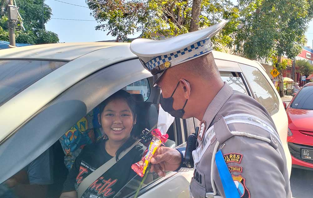 Petugas Polres Blitar Ktoa saat memberikan hadiah berupa bunga dan cokelat kepada pengendara yang tertib lalu lintas.
