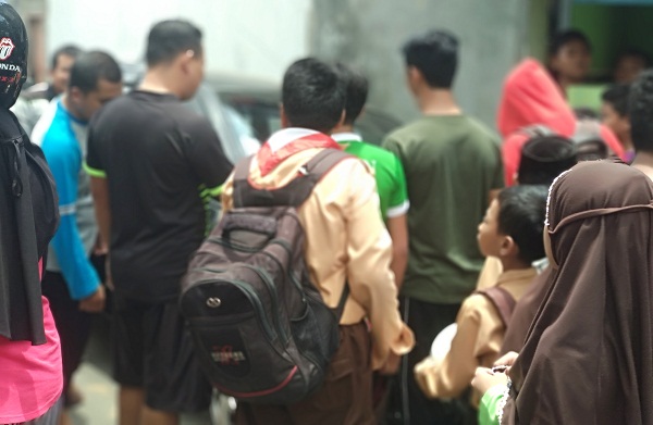 Murid dan orang tua bergerombol menyaksikan Honda Jazz yang terperosok ke selokan. foto: YUNIARDI S/BANGSAONLINE