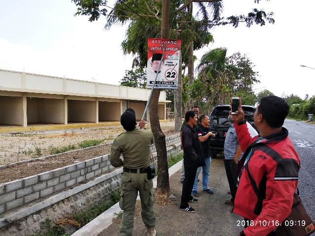 Petugas menertibkan alat peraga kampanye (APK) yang menyalahi aturan. 
