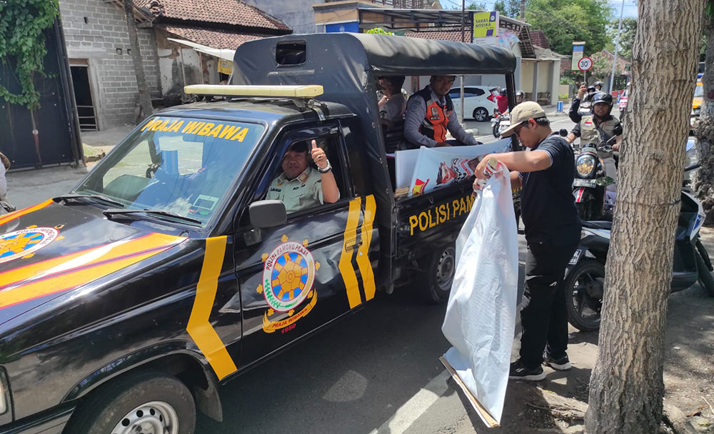 Petugas Satpol PP Kota Blitar saat mencopot APK yang dipaku di pohon.