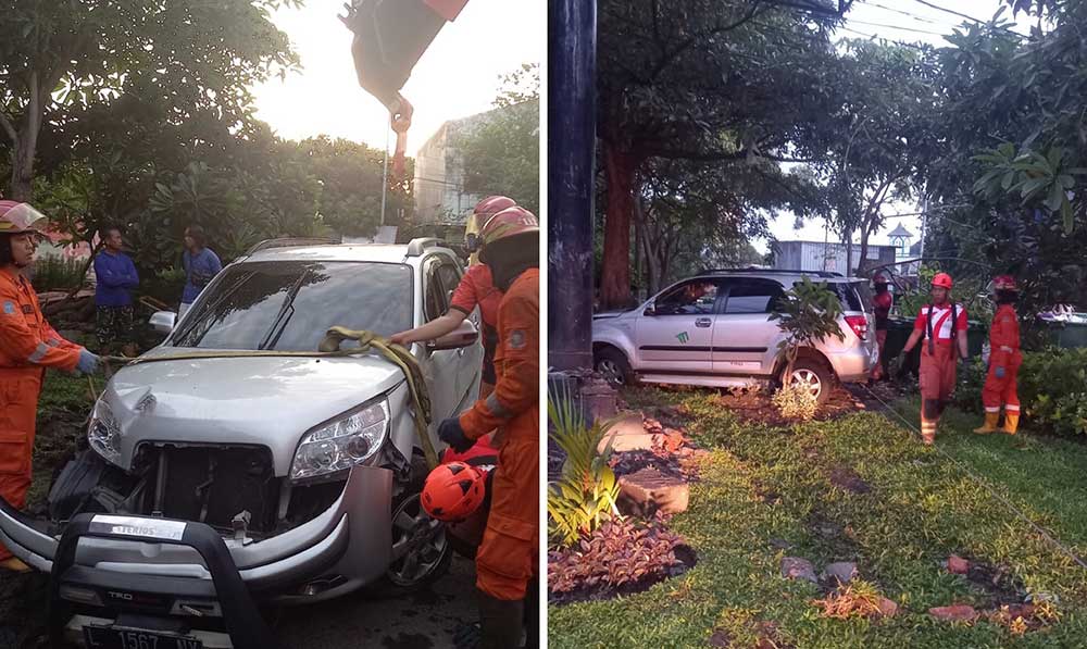Petugas Damkar Surabaya saat berupaya mengevakuasi mobil anggota Polri yang masuk ke taman di Jalan Raya Menur.