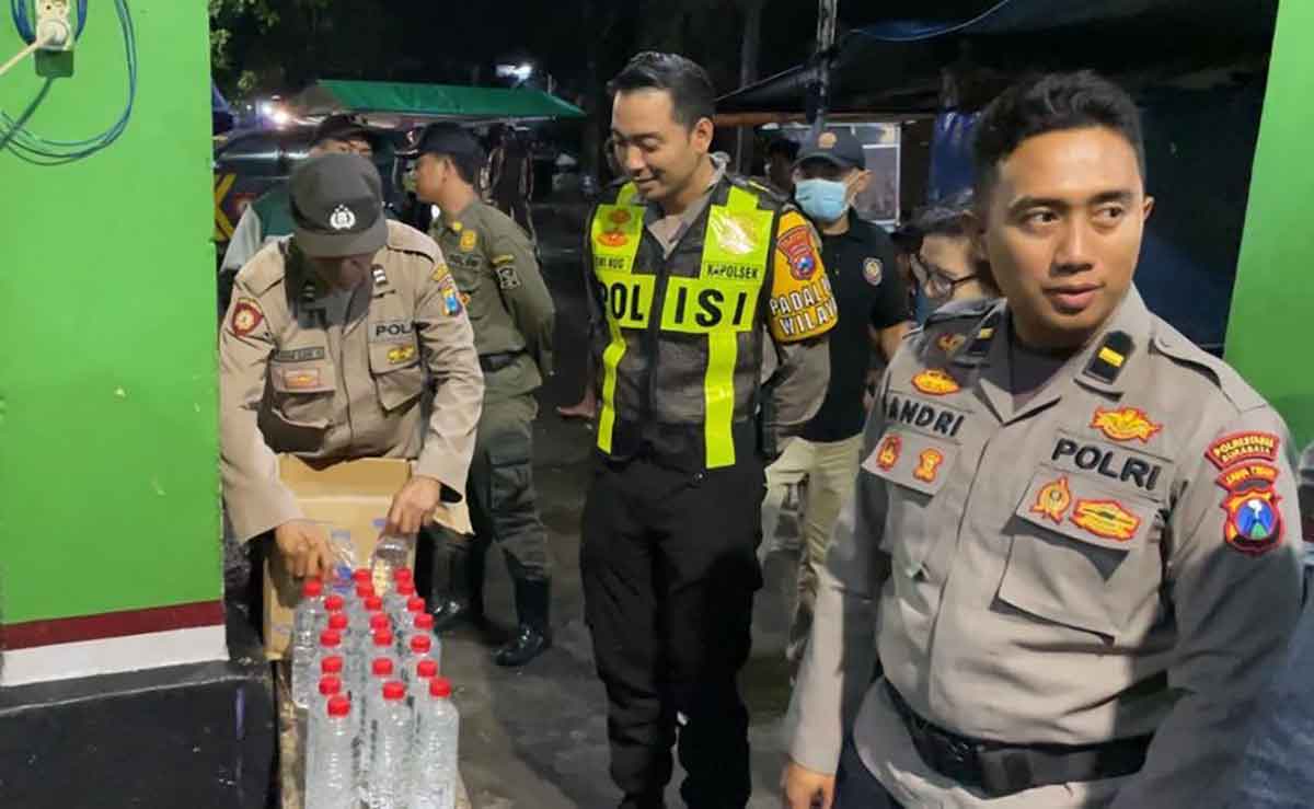 Petugas dari Polsek Simokerto saat menyita botol arak dari seorang warga di Jalan Kertopaten, Surabaya.