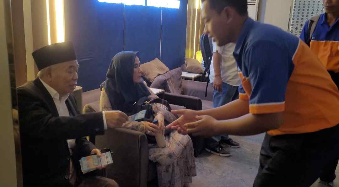 Prof Dr KH Asep Saifuddin Chalim dan istrinya Nyai Hj Alif Fadhilah membagikan uang kepada porter di stasiun kereta api Pasar Turi Surabaya. Foto: bangsaonline