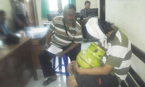 Tersangka bersama barang bukti tabung gas elpiji saat diamankan di mapolsek plemahan. (foto: dendi martoni/BANGSAONLINE)
