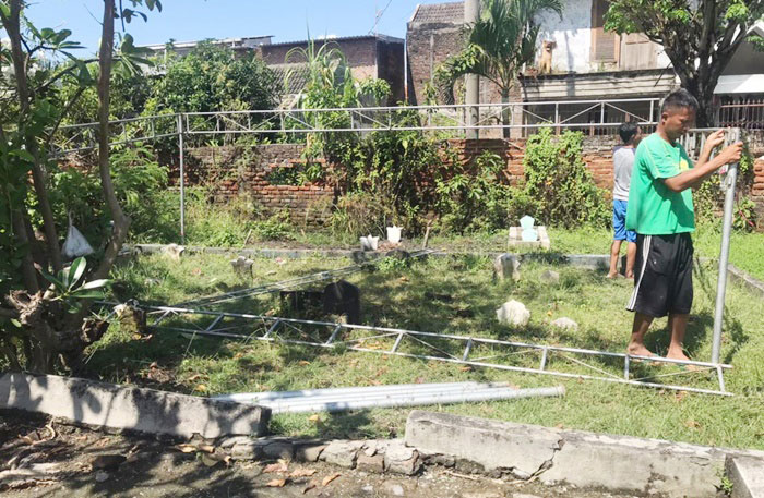 Warga sedang mencopot kembali tenda terop yang akan digunakan dalam proses penggalian makam korban.