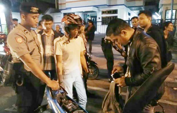 Petugas saat memeriksa barang bawaan pengendara bermotor.