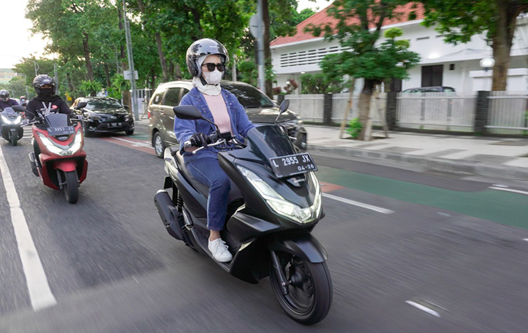 Ilustrasi seorang perempuan bermotor dengan riding gear yang aman dan benar.