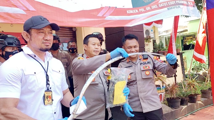 Kapolsek Tambaksari menunjukkan sajam berupa celurit berukuran ekstra panjang yang dipergunakan tersangka membacok korban.