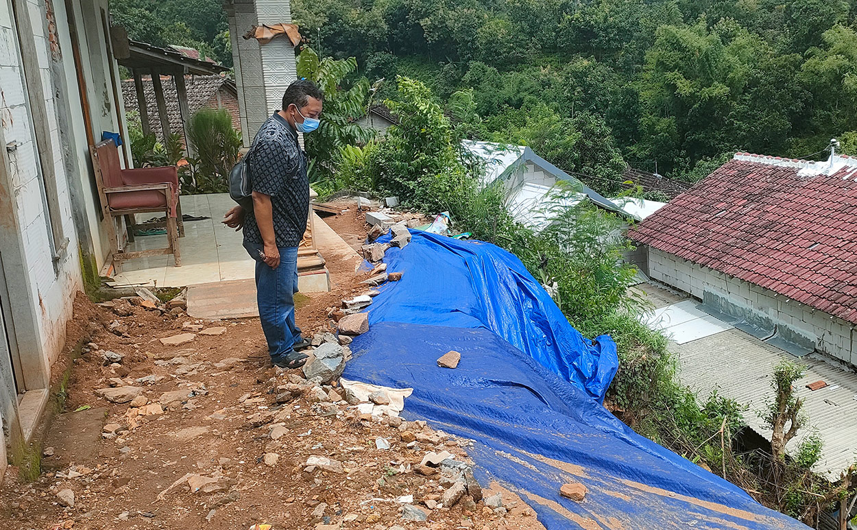 Kondisi tanah retak yang telah ditutupi terpal sebagai antisipasi longsor. Tampak beberapa rumah penduduk di bawahnya. foto: MUJI HARJITA/ BANGSAONLINE