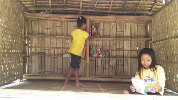 Dua anak sedang asik mambaca buku di TBM Kolare, Desa Lapataman, Kecamatan Dungkek. foto: rahmatullah/ BANGSAONLINE