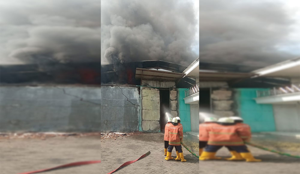 Petugas saat mencoba memadamkan gudang di Margomulyo yang terbakar.