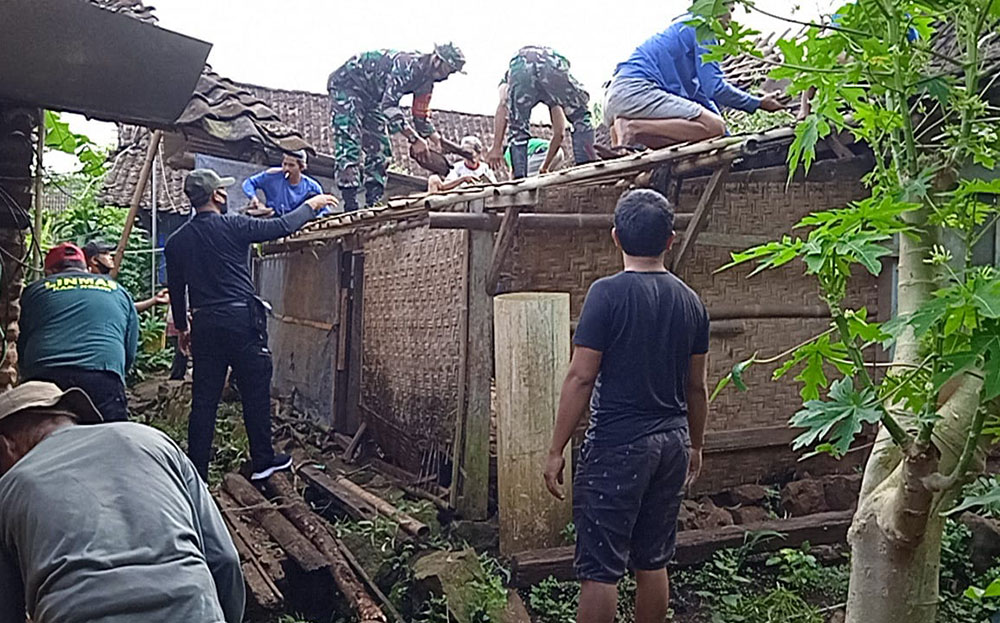 Warga bersama babinsa gotong royong membenahi rumah warga yang tertimpa pohon tumbang.