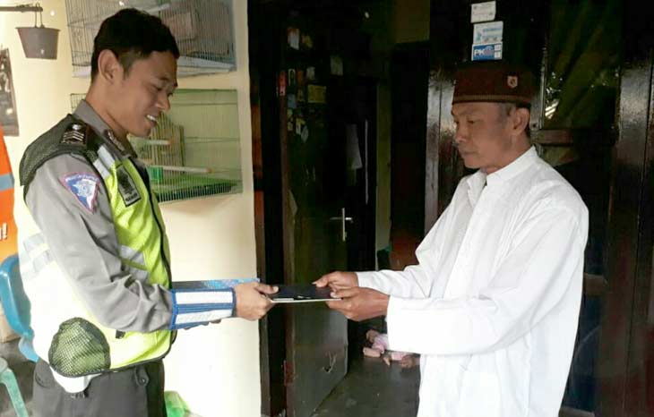 Dua anggota Satlantas Polres Pasuruan Kota saat menyerahkan BPKB kepada pemiliknya, Senin (04/01/2019). foto: ANDY F/ BANGSAONLINE 