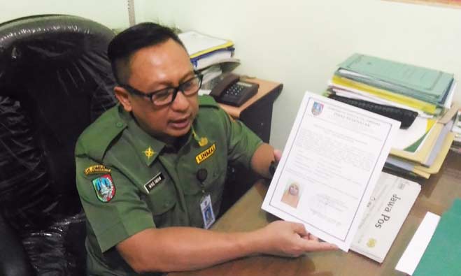 Mas Imam Ali Afandi menunjukan contoh sertifikat layak sehat yang dikeluarkan oleh Dinkes. foto: Romza/ BANGSAONLINE.