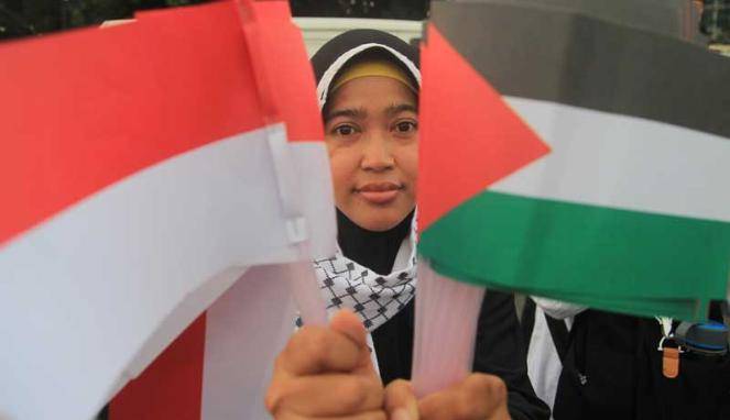  Seorang perempuan memegang Bendera Indonesia & Palestina saat aksi solidaritas mengutuk penyerangan Masjid Al-Aqsa oleh Israel di Jakarta, Jumat (14/11/2014). Foto: Vivanews.com
