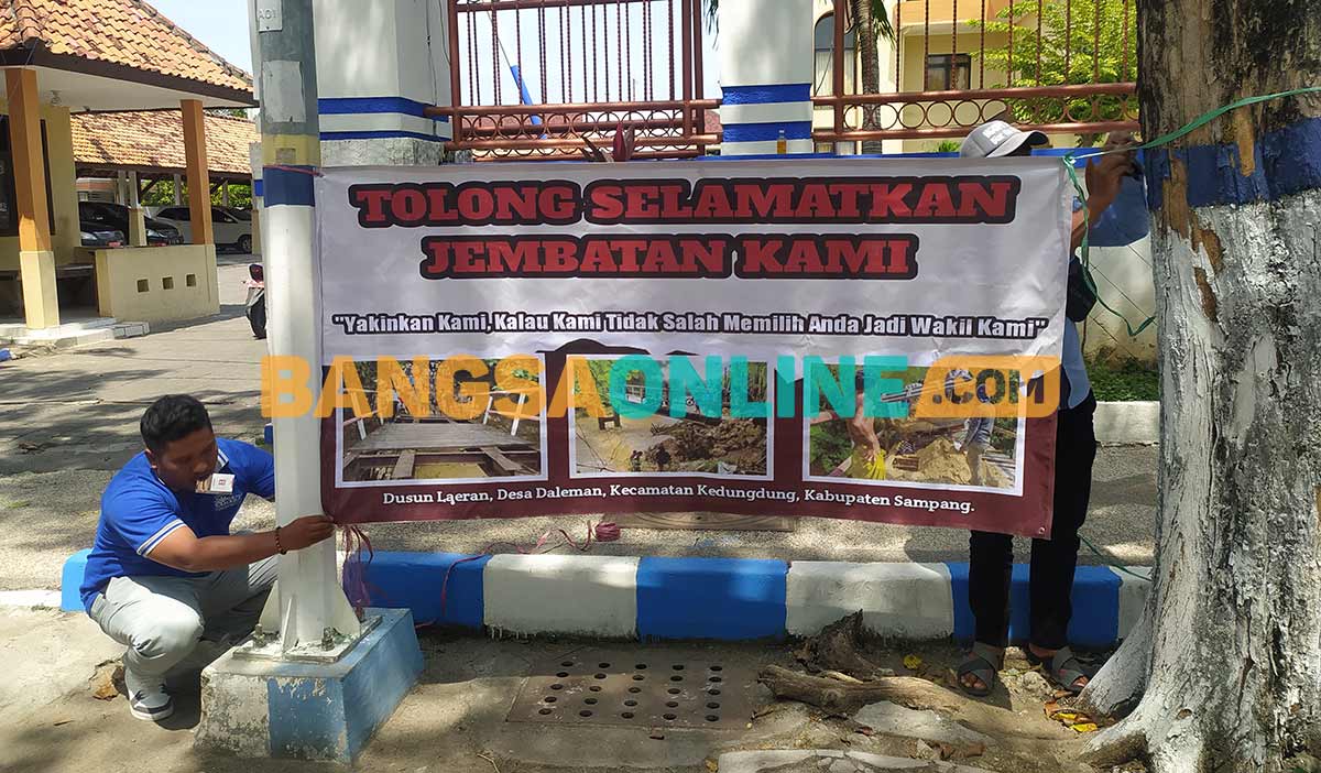 Pemuda di Desa Daleman saat memasang banner di pintu utama gedung DPRD Sampang. Foto: MUTAMMIM/BANGSAONLINE