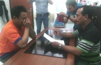 Tersangka menutupi wajahnya di hadapan penyidik, kemarin. foto : nanang ichwan/BANGSAONLINE