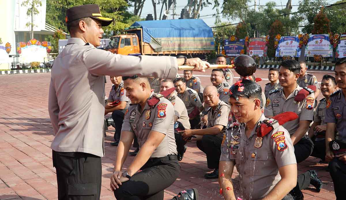 Kapolres Gresik AKBP Rovan Richard Mahenu saat menyiramkan air kembang kepada anggota yang naik pangkat. Foto: Ist