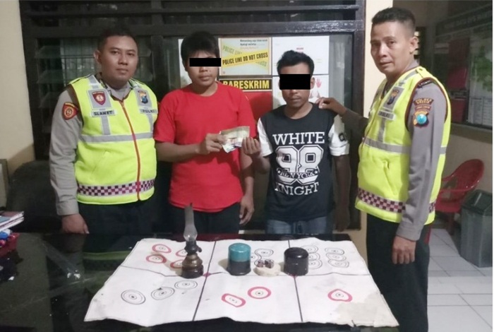 Petugas saat mengekspos dua tersangka judi dadu. foto: SYUHUD A/ BANGSAONLINE