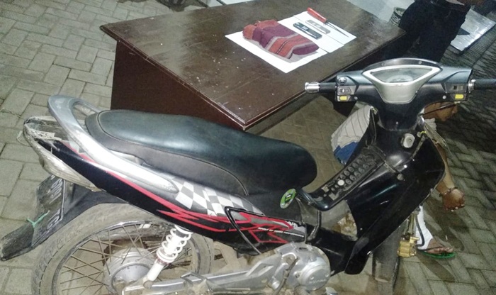 Tersangka pembunuh Metty alias Slamet Pujianto (di balik motor) dengan kaki kanan terbalut akibat berusaha kabur. Petugas juga mengamankan barang bukti berupa sangkur berada di atas meja.
