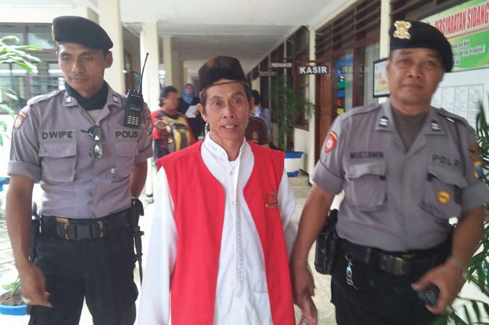 Mbah Parman dikawal polisi usai mengikuti sidang.