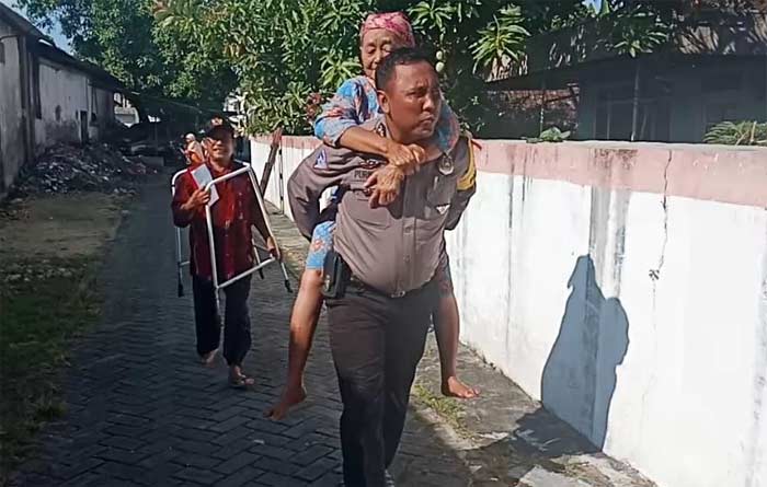 Bripka Purnomo saat menggendong nenek Sri Sutini menuju TPS.