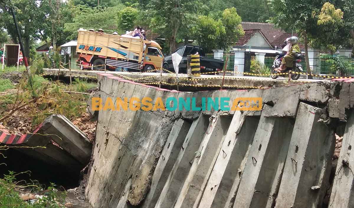 Penahan badan jalan yang ambrol akibat terkikis aliran sungai. Foto: BAMBANG DWI JULIANTO/BANGSAONLINE
