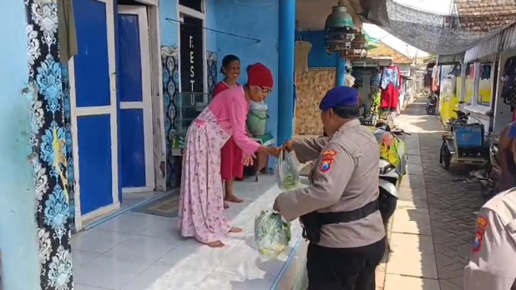 Anggota saat membagikan sayur ke salah satu warga