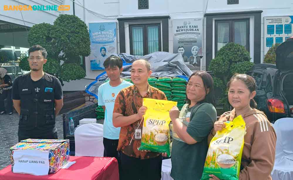 Kasi Intelejen Kejari Kabupaten Kediri, Iwan Nuzuardhi foto bersama warga pembeli beras murah. Foto: Muji Harjita/Bangsaonline.