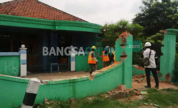Para pekerja saat membongkar bangunan liar di atas drainase. foto: arif kurniawan/ BANGSAONLINE