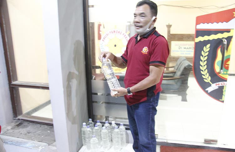 Petugas saat mengamankan minuman keras sebagai barang bukti.