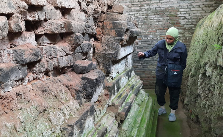 Salah seorang pengunjung saat mengamati kaki Candi Dorok yang tampak berlumut. (foto: MUJI HARJITA/ BANGSAONLINE)