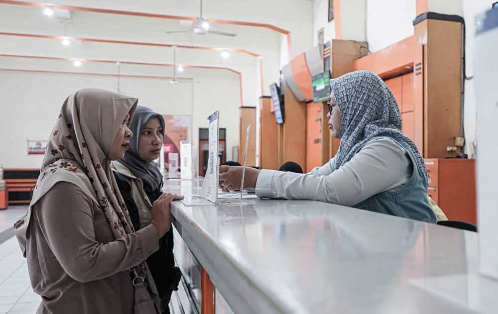 Petugas Kantor Pos Kediri saat melayani keluarga penerima manfaat yang mencairkan bantuan PPSE. Foto: Ist.