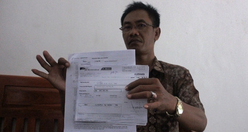Sisyanto menunjukkan dokumen bahwa pembelian mobilnya yang dilakukan secara cash. (Suwandi/BangsaOnline.com)
