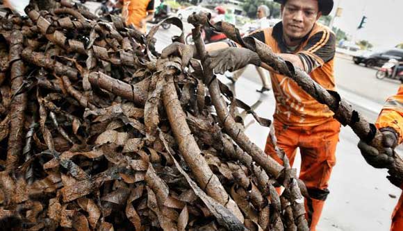 Petugas saat mengambil kulit kabel yang menyumbat drainase di Jalan Medan Merdeka. foto: liputan6