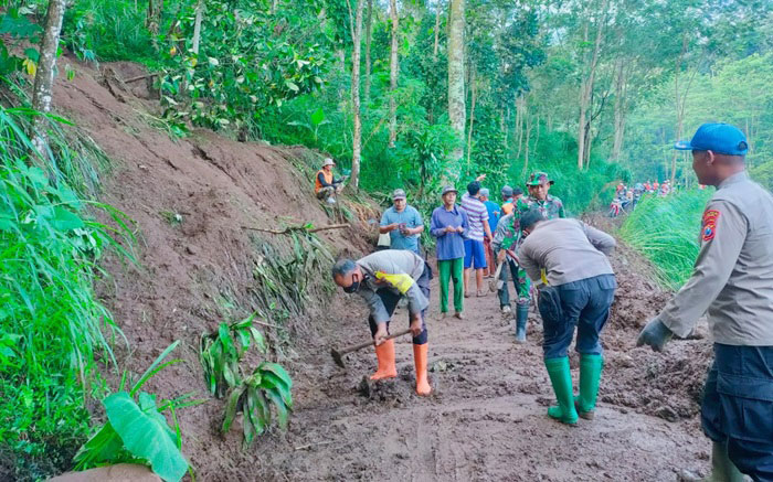 Anggota Polsek dan Koramil Jogorogo bersama warga melakukan kerja bakti membuka jalan yang tertutup longsor.