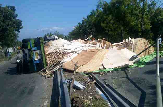 Truk yang terguling beserta muatan triplek hampir menutup seluruh badan jalan. (foto: soewandito/BANGSAONLINE)
