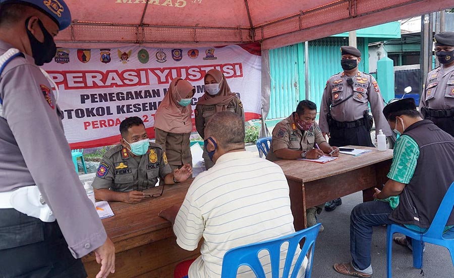 Petugas saat menindak pengguna jalan yang tidak pakai masker. (foto: ist)