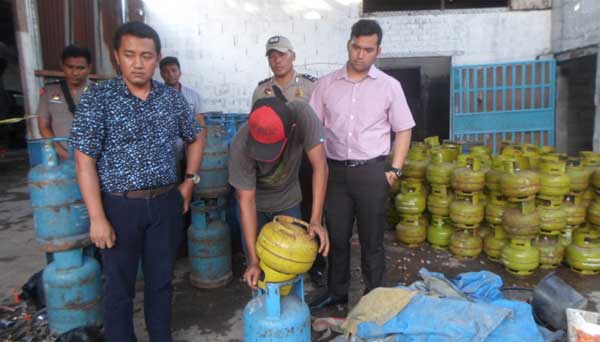 OPLOS: Salah satu pekerja sedang mempraktekkan cara mengoplos elpiji dihadapan petugas. foto: catur andy erlambang/ BANGSAONLINE