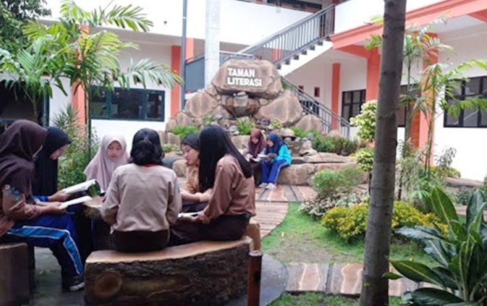 Para pelajar SMP Negeri 1 Kota Mojokerto sedang asyik baca buku perpustakaan di Taman Sekolah.