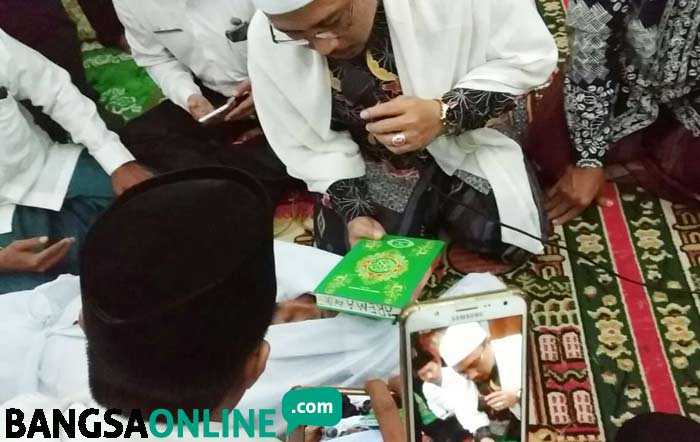 Mattawi saat disumpah pocong dan disaksikan forpimka, pengurus NU, MUI, serta warga. foto: GANDA/ BANGSAONLINE